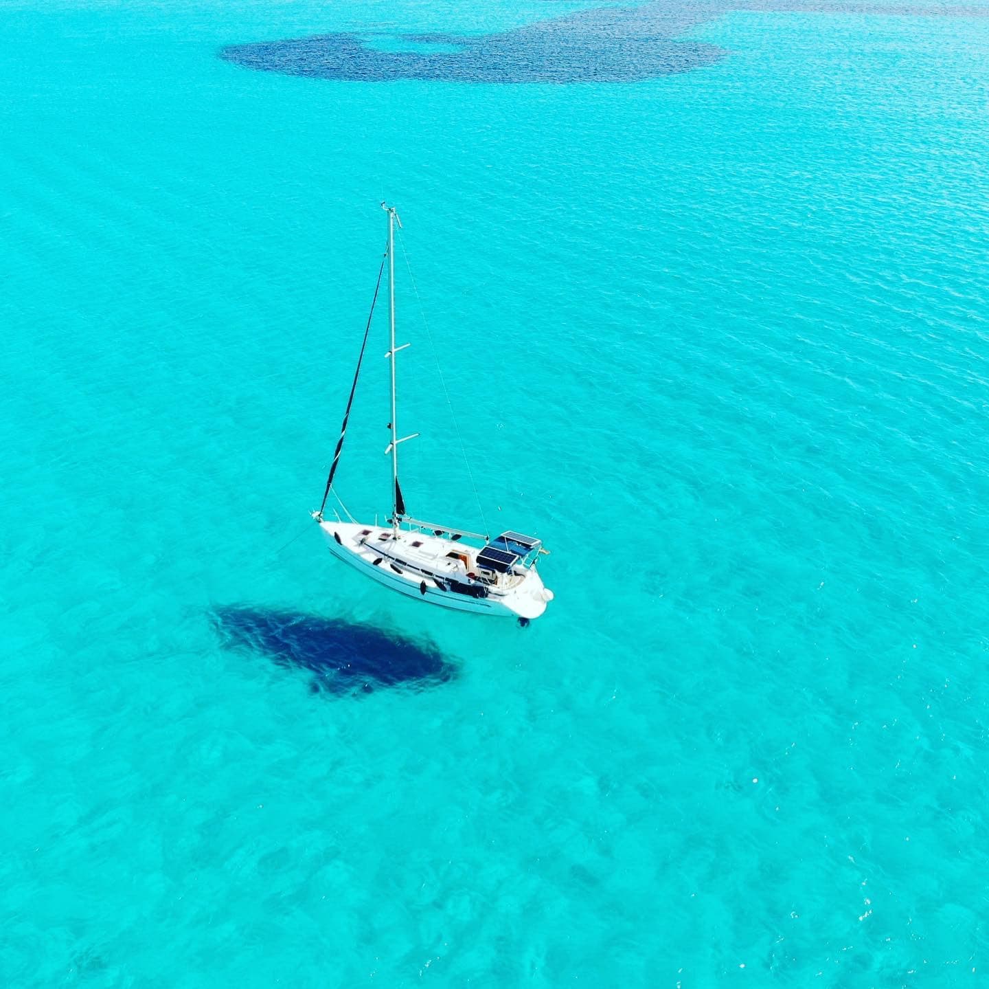 Vista cenital de un velero sobre aguas turquesa