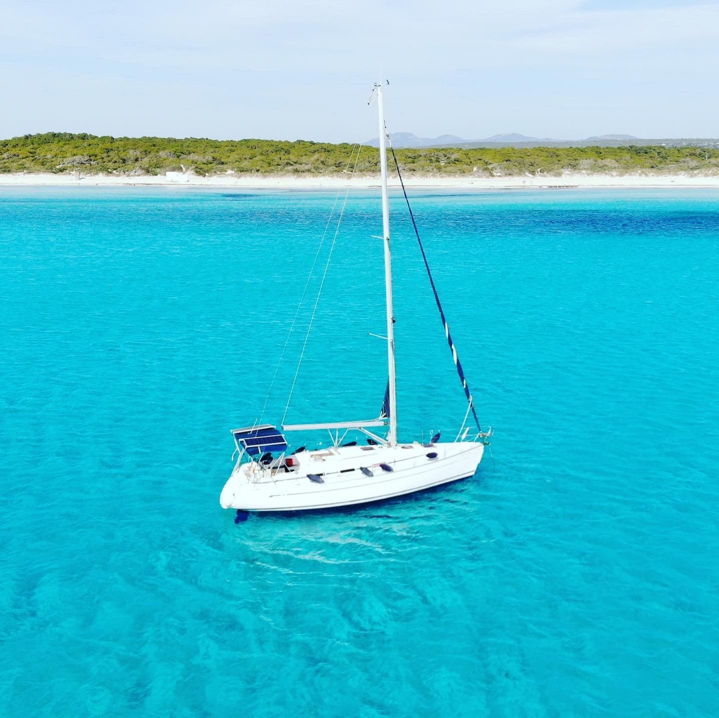 Velero fondeado frente a una playa de arena blanca en Mallorca