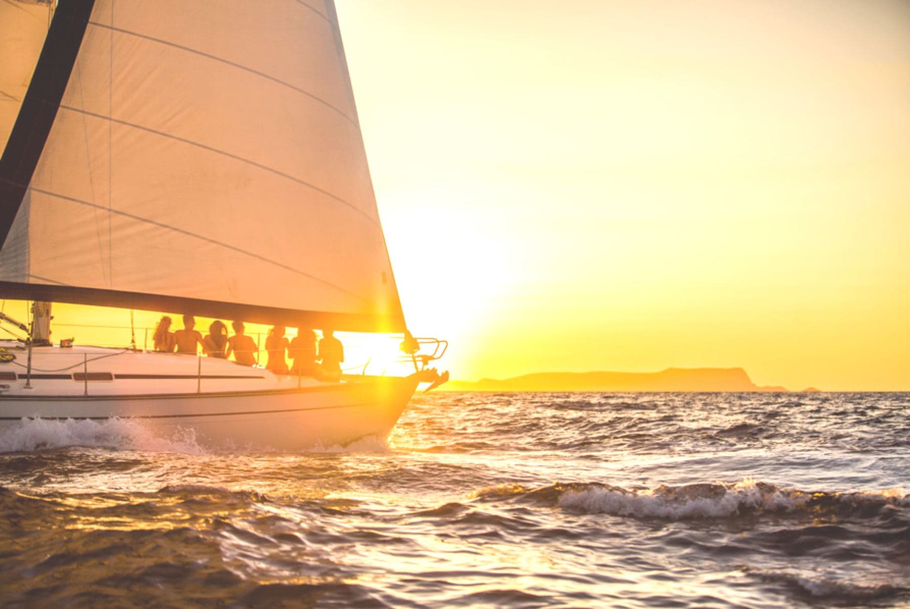 Velero navegando con las velas izadas al atardecer